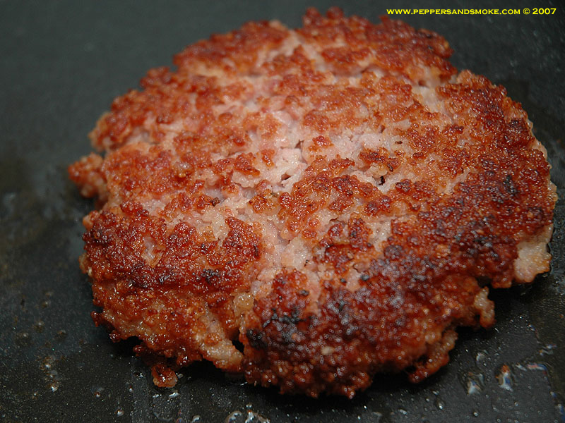 Bacon burger patty cooking in a skillet